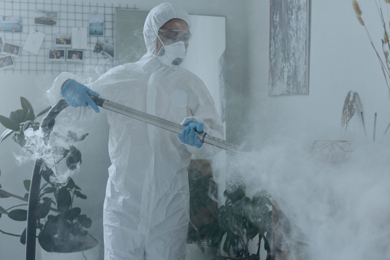 Woman in PPE cleaning a plant with a chemical spray