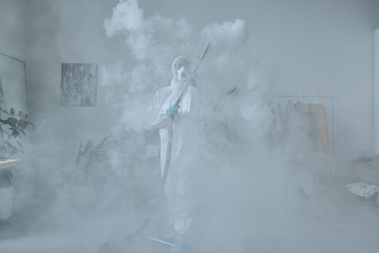 Woman in PPE cleaning a room with a chemical spray