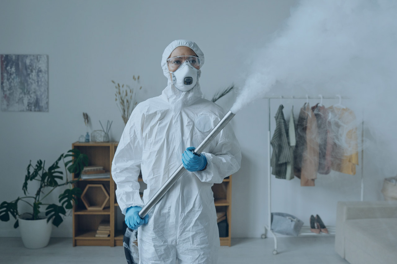 Woman in PPE holding a chemical spray device